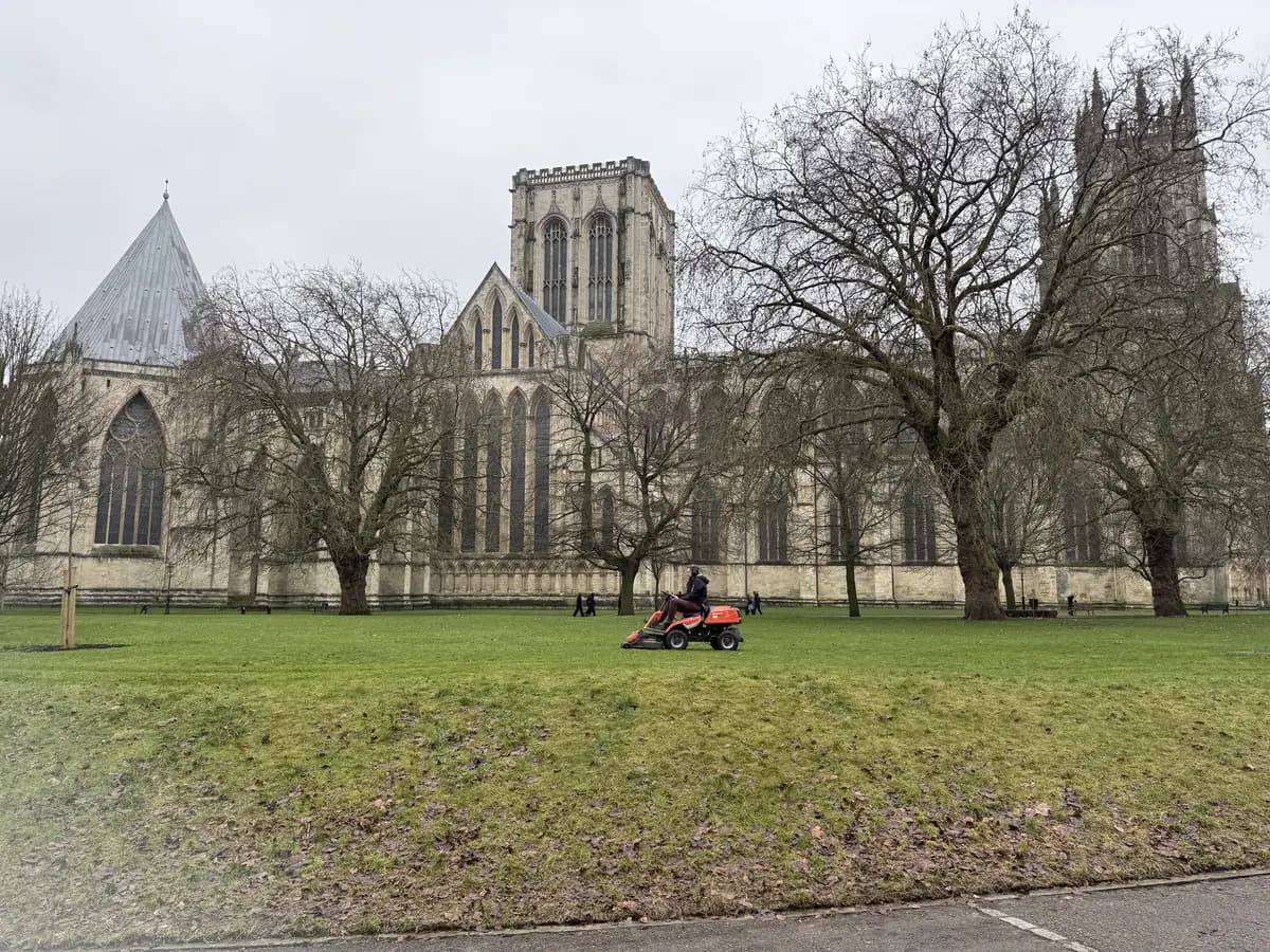 Ride-on mower working a lawn beneath a cathedral in winter