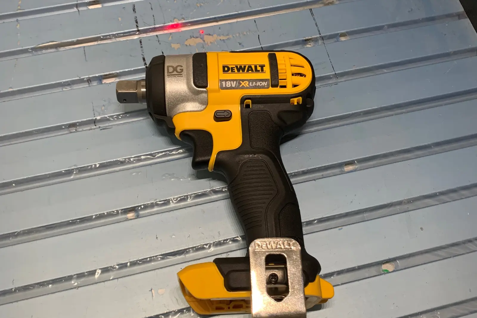 Cordless impact driver on the laser engraver bed with the aiming dot visible and a client logo marked on the casing