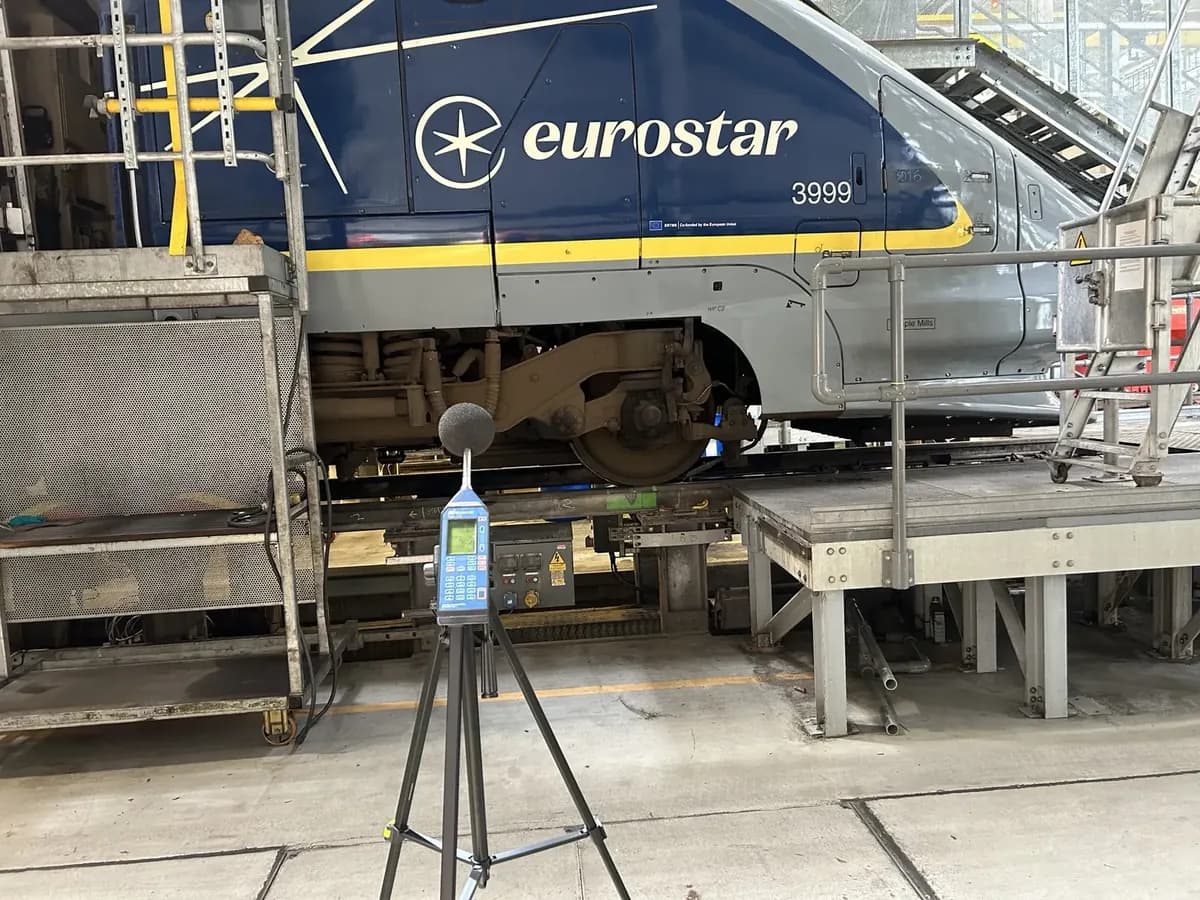 Tripod-mounted sound level meter during a workplace noise assessment in a rail maintenance depot