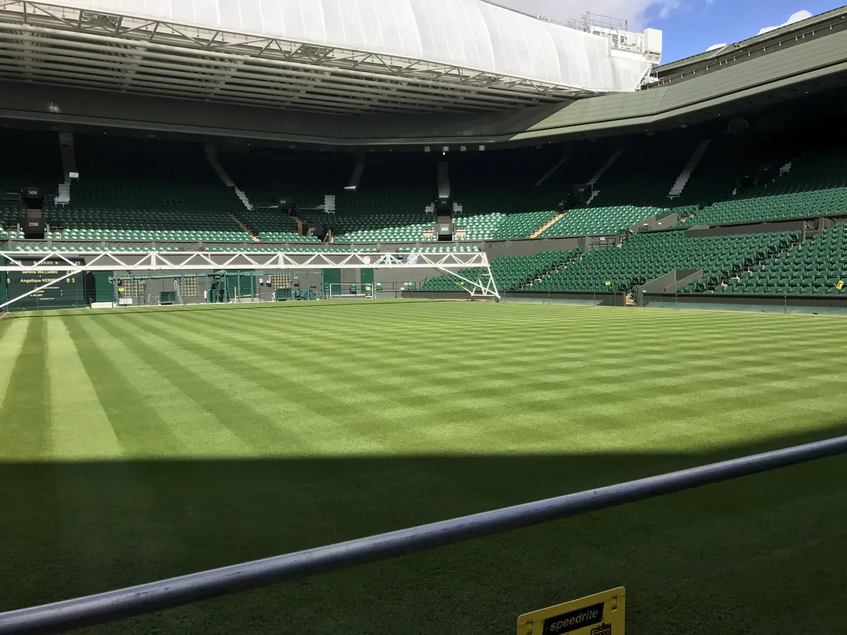 Striped show-court turf under an open roof at a Grand Slam tennis venue