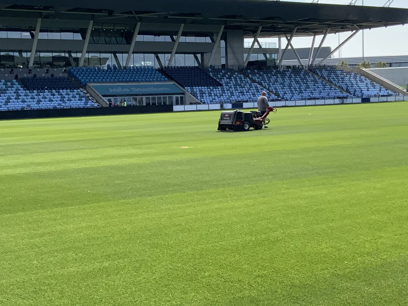 Pedestrian aerator working a stadium pitch in front of the stands