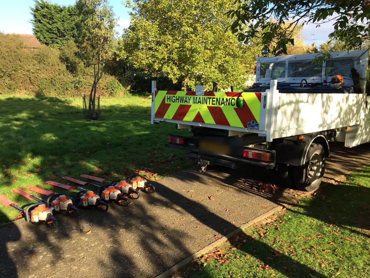 Row of petrol hedge trimmers laid out beside a highway maintenance truck for vibration testing